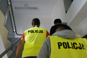 Policjanci prowadzą osobę zatrzymaną