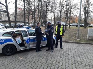 Komandant Powiatowy Policji w Będzinie oraz policjant ruchu drogowego wraz ze Starostą Powiatu Będzińskiego stojący obok radiowozu