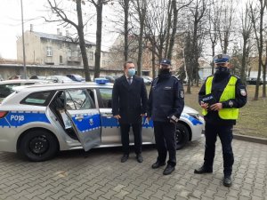 Komandant Powiatowy Policji w Będzinie oraz policjant ruchu drogowego wraz ze Starostą Powiatu Będzińskiego stojący obok radiowozu