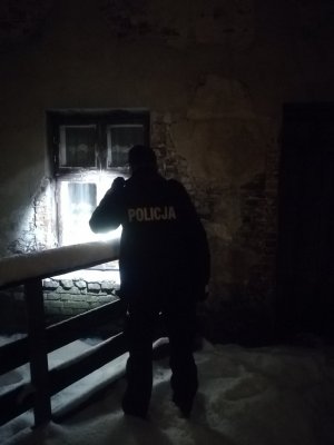 Policjant świecący latarką w okno budynku