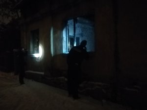 Policjanci świecący latarkami i zaglądający przez okno do pustostanu