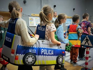 Na zdjęciu dzieci korzystające z mobilnego miasteczka ruchu drogowego są przebrane za samochody.
