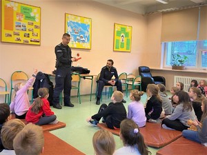 Na zdjęciu policjanci przemawiają do dzieci podczas wizyty w przedszkolu.