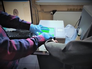 Zdjęcie przedstawia pobieranie odcisków palca przez technika kryminalistyki.